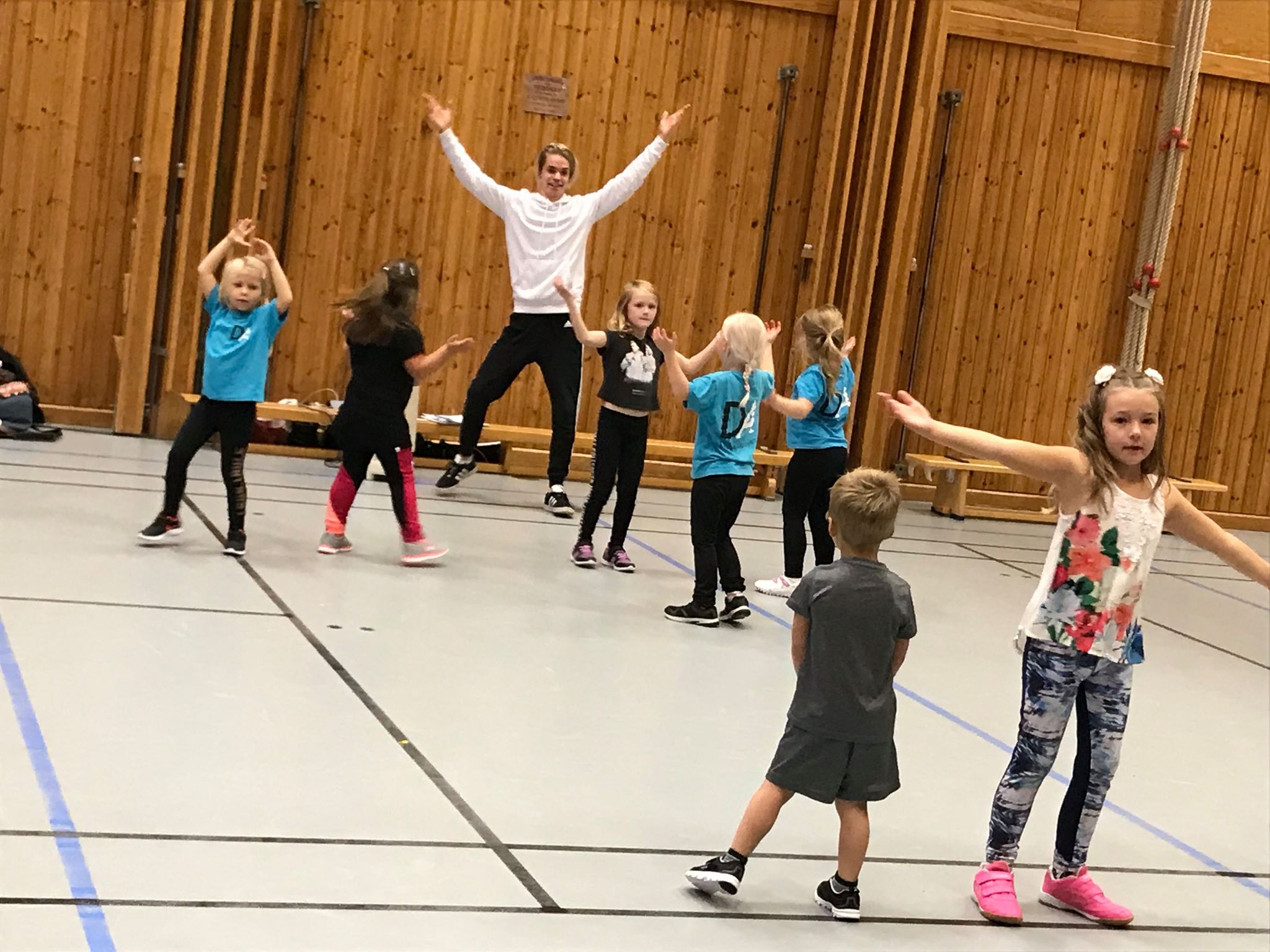 Barn dansar i en hall med en lärare