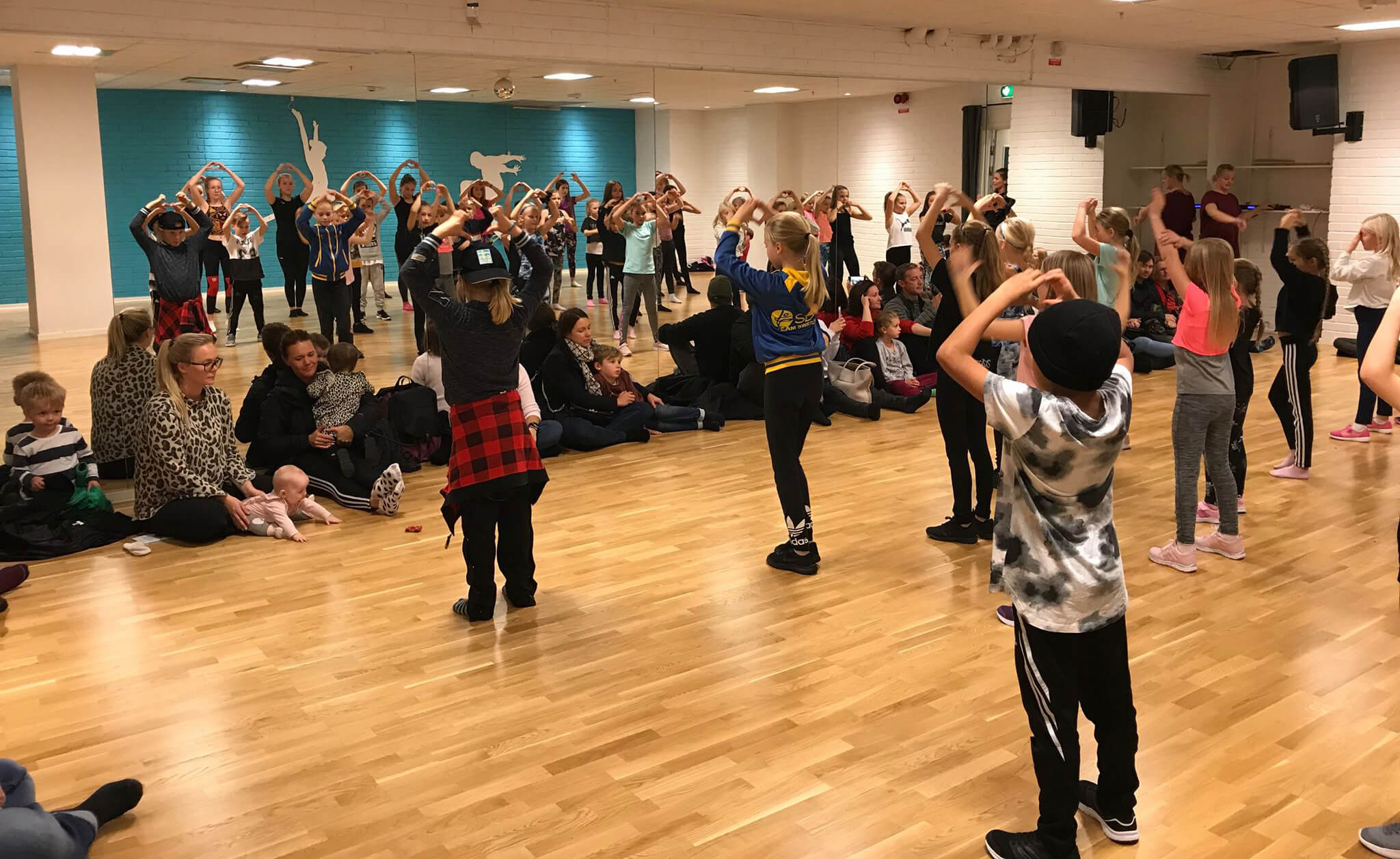 Barn dansar framför spegel och föräldrar